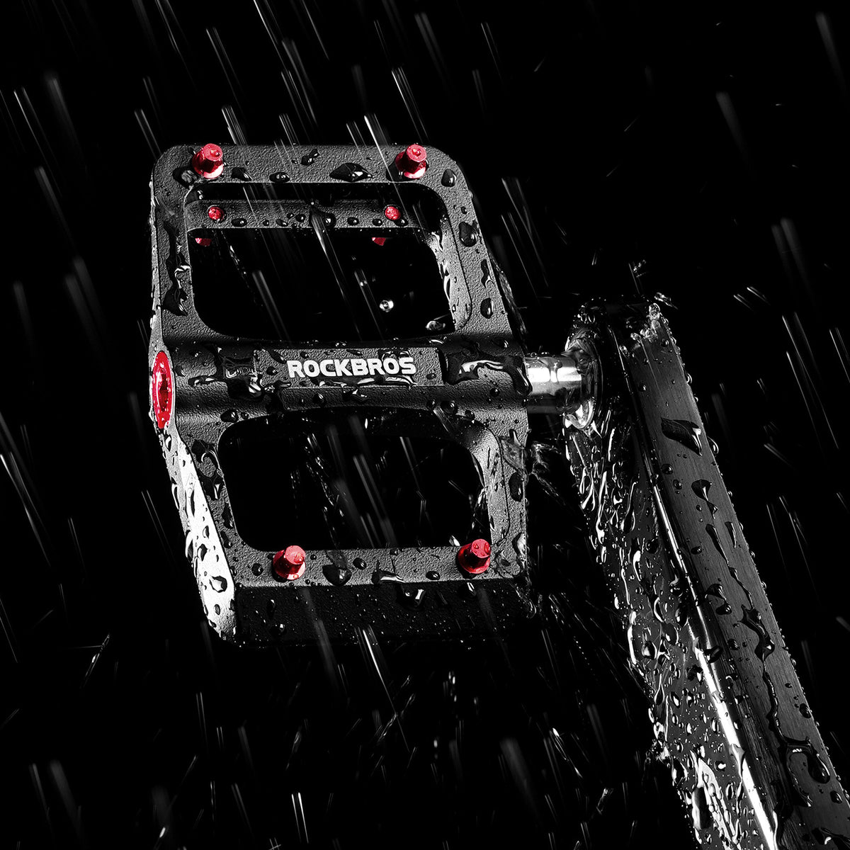 Pair of black ROCKBROS flat pedals with red traction pins and silver axles.